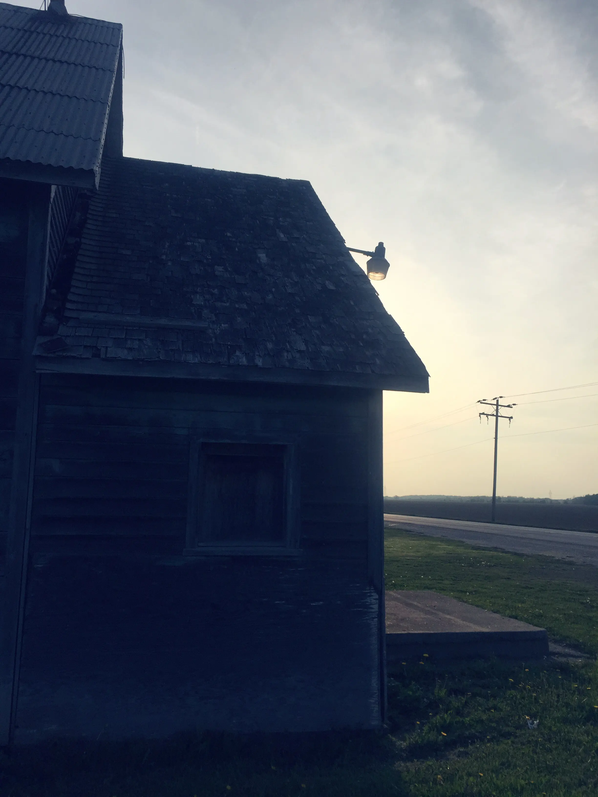 Blick auf eine Scheune auf einem Feld vor einem bewölkten Himmel.